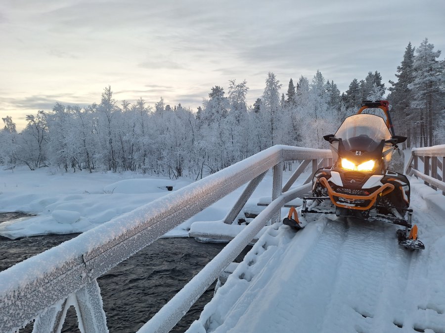 Moottorikelkka sillalla lumimaisemassa